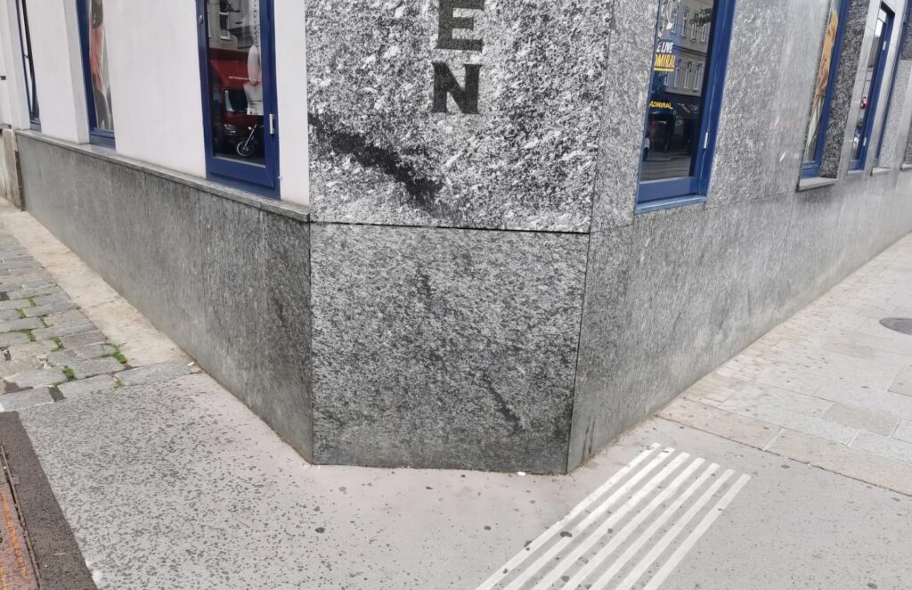 Ecke eines Gebäudes mit grauer Granitfassade.